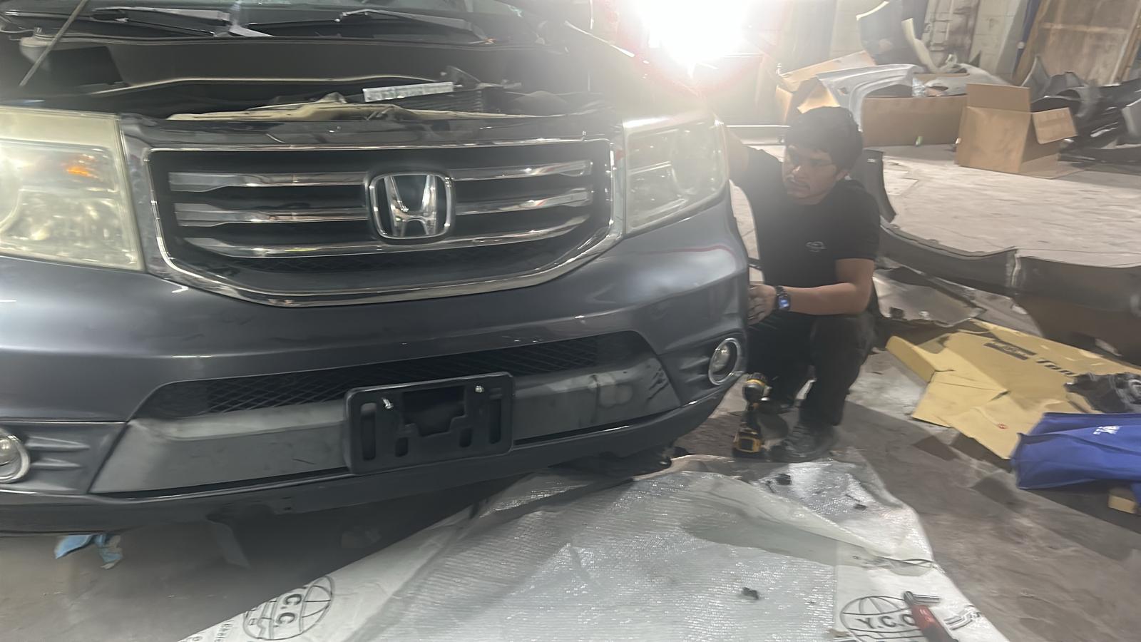 Technician fitting a bumper on a Honda Pilot