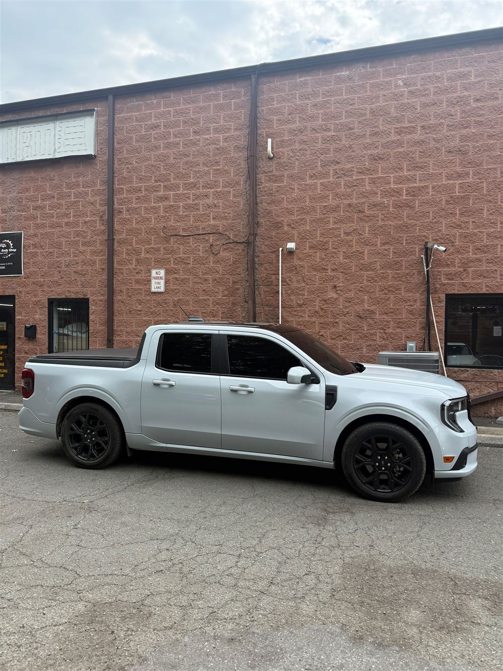 White Ford Maverick pickup with black wheels outside the shop