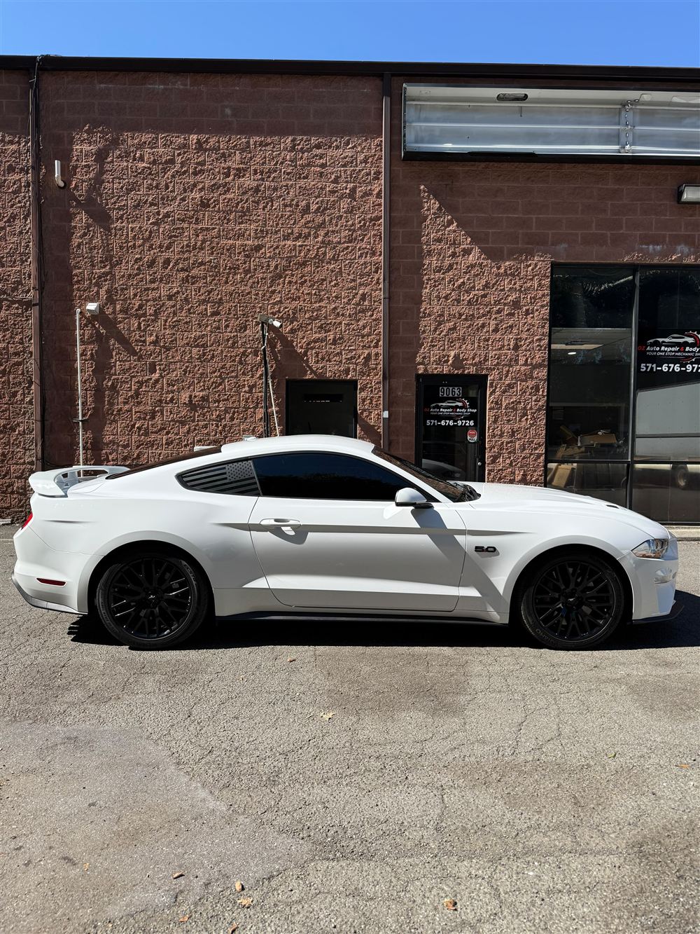 White Ford Mustang GT with black wheels outside the shop