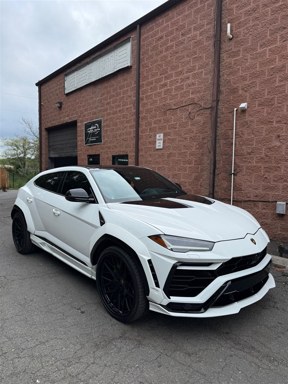 White Lamborghini Urus with a black hood outside the shop