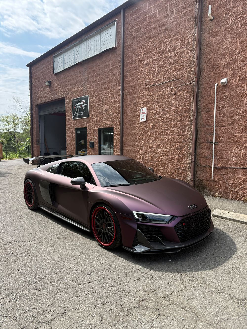 Satin purple Audi R8 with red-lipped wheels outside the shop